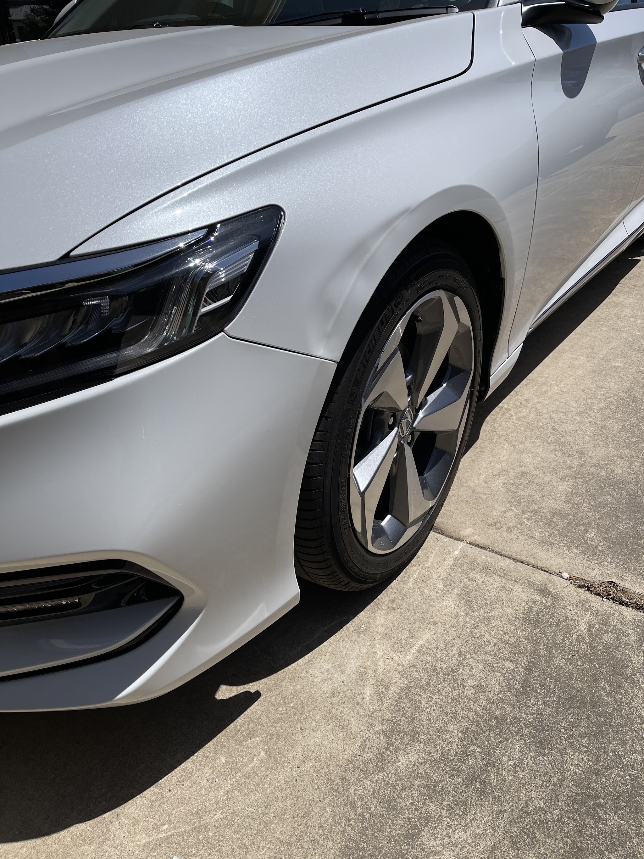 Repaired front guard and wheel arch on a silver Honda