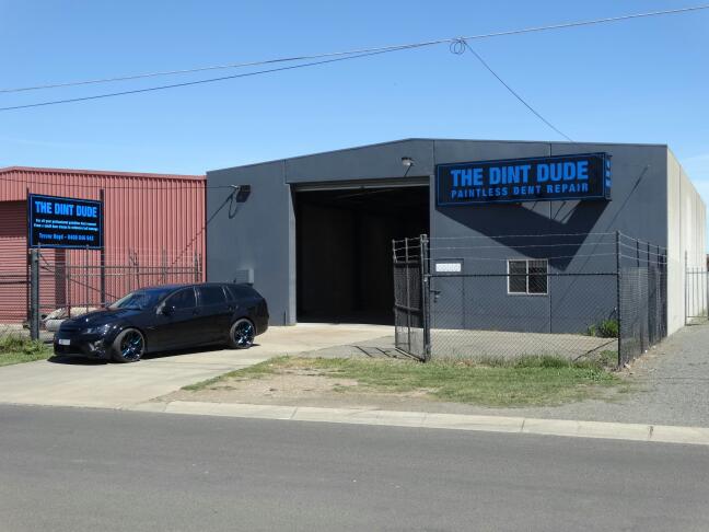 The Dint Dude workshop in Delacombe, a grey shed with the roller door open and the sign above it