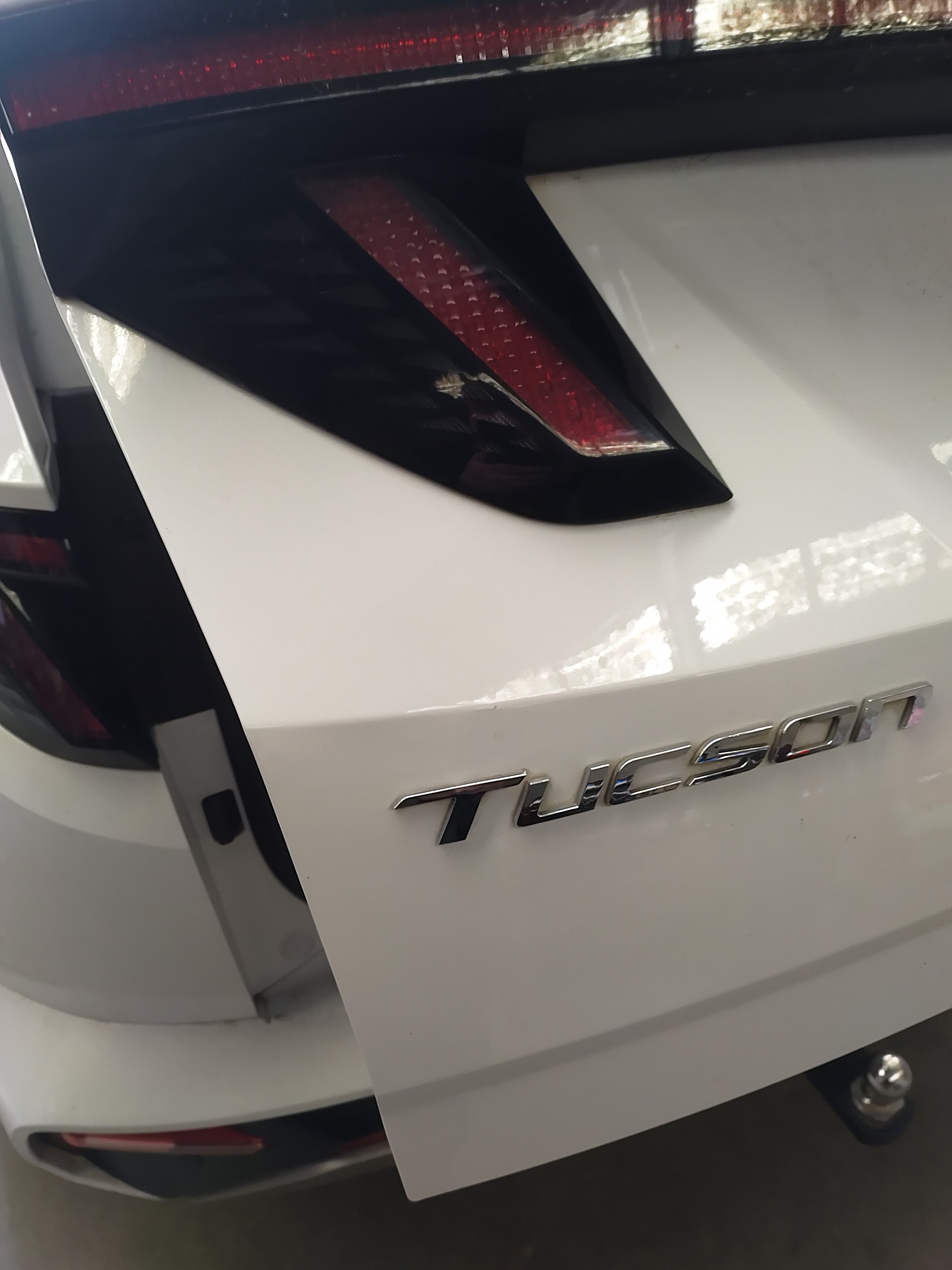 The same white Hyundai Tucson tailgate after paintless dent repair, panel now straight